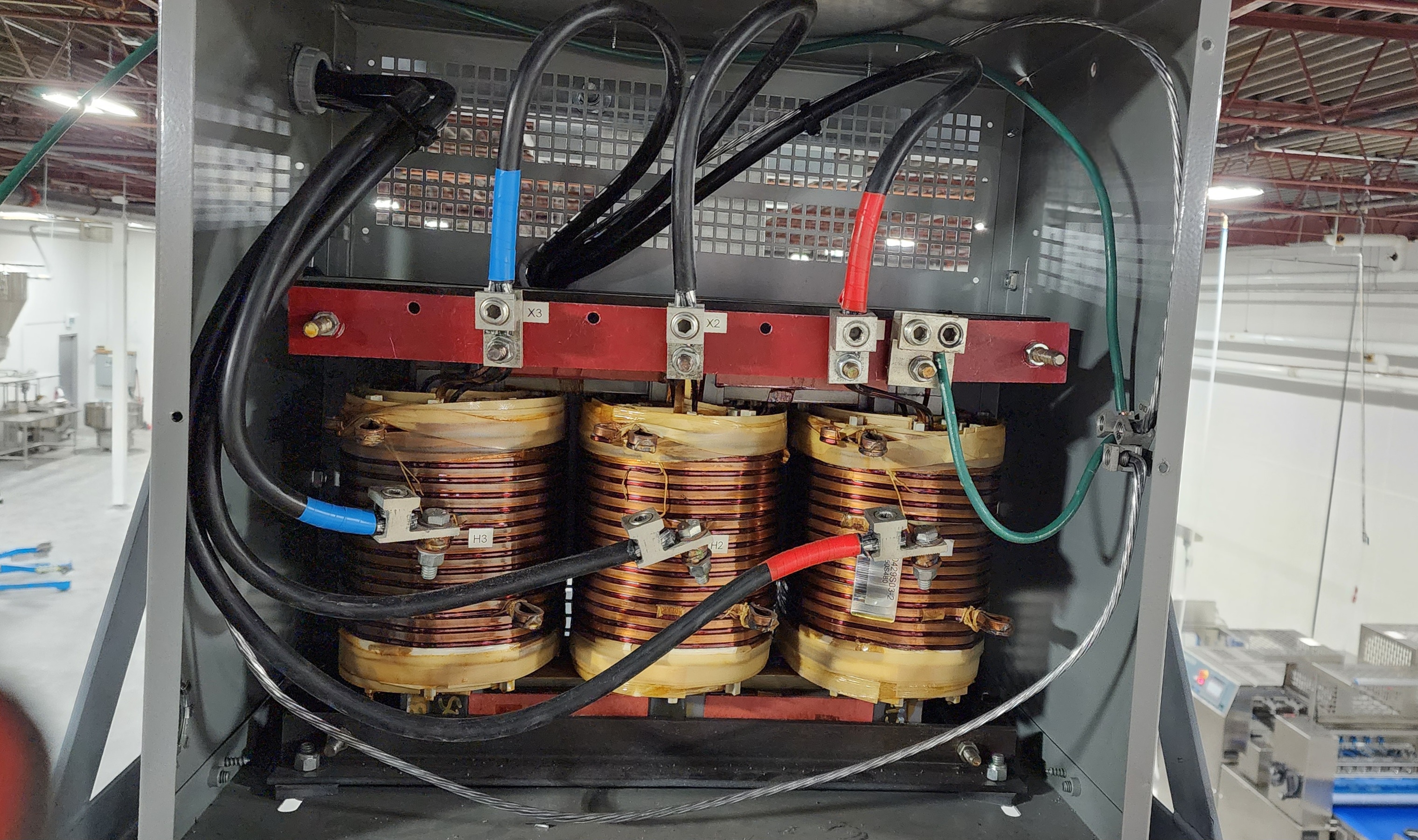 Commercial transformer with copper windings and red busbar installed by Actus Electric