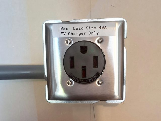 NEMA 14-50 outlet on a steel cover plate, labelled Max. Load Size 40A, EV Charger Only, with grey conduit entering from the side