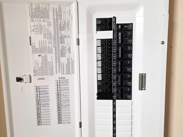 New breaker panel with the door open, the circuit directory on the door filled in by hand
