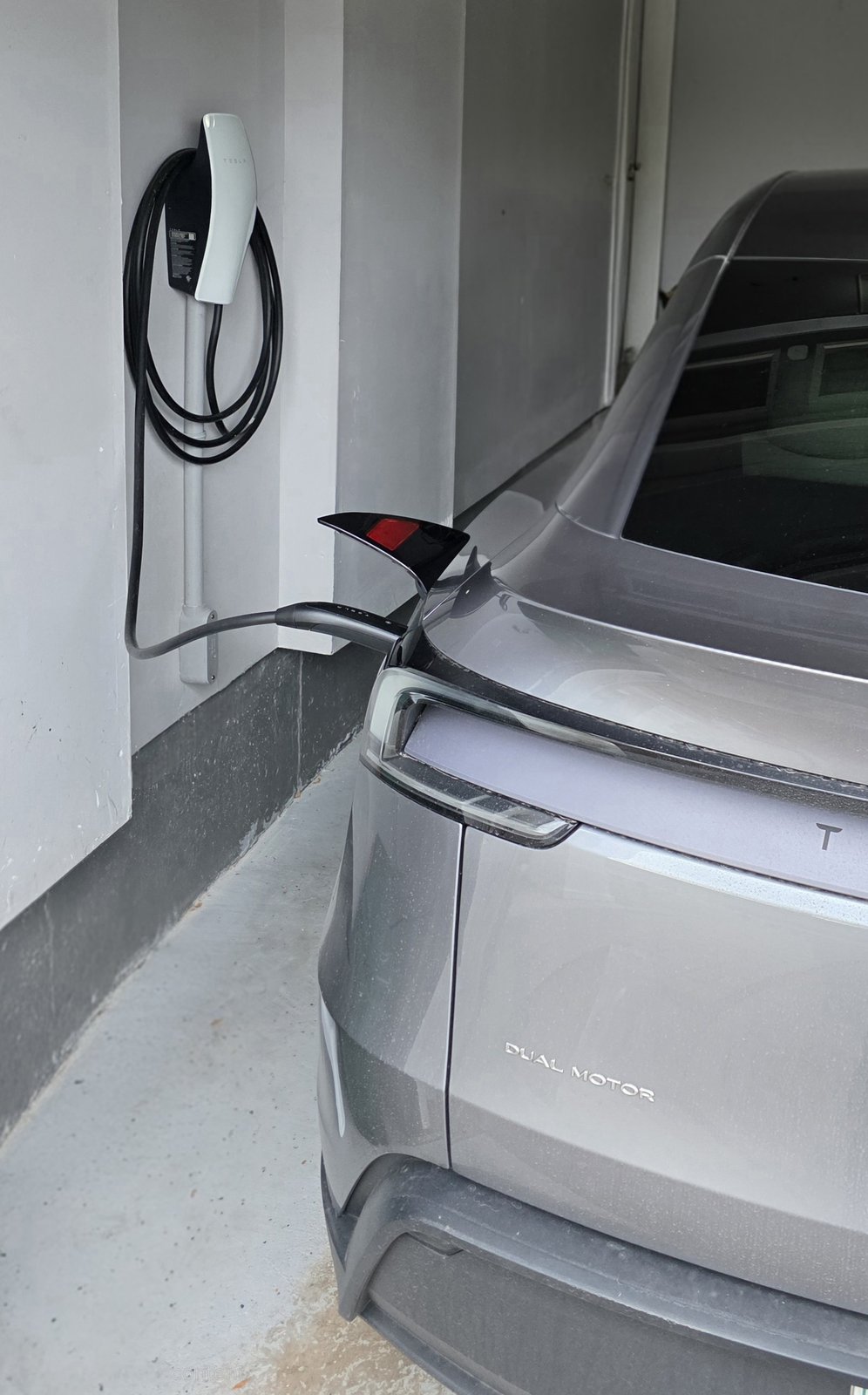 Tesla Wall Connector installed and charging a Tesla vehicle in a residential garage