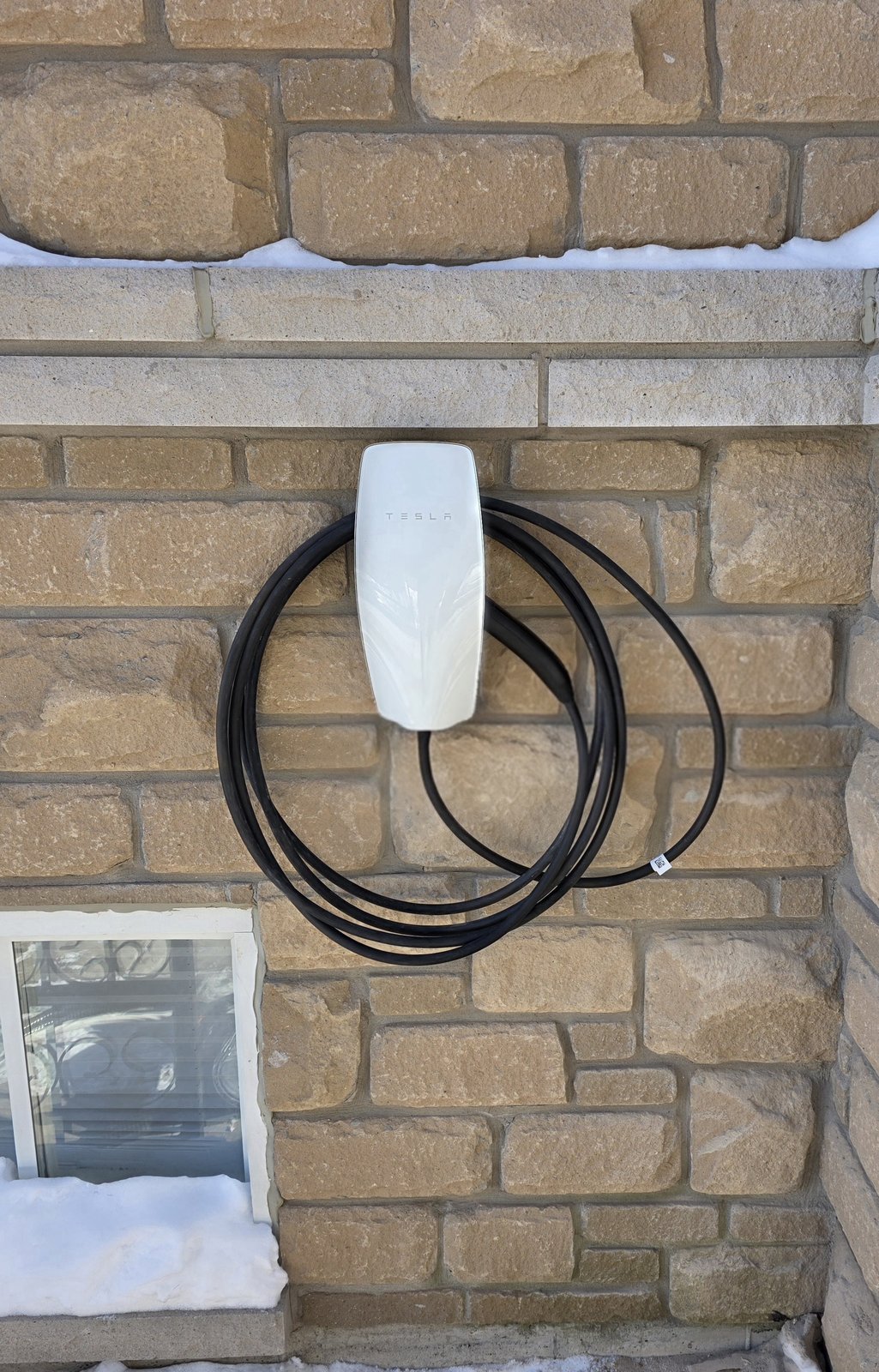 Tesla EV charger installed outside on brick wall — Etobicoke home
